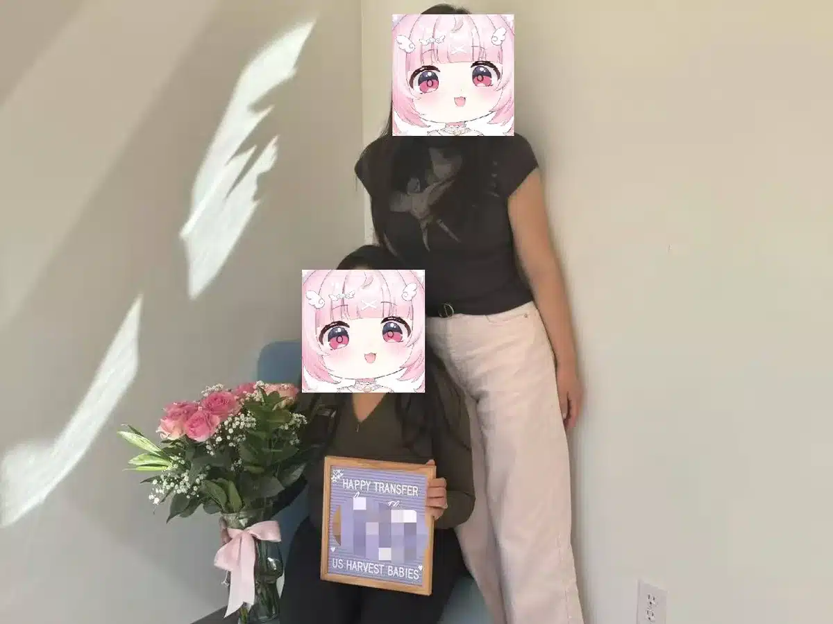 A surrogate and an intended mother standing side by side with flowers